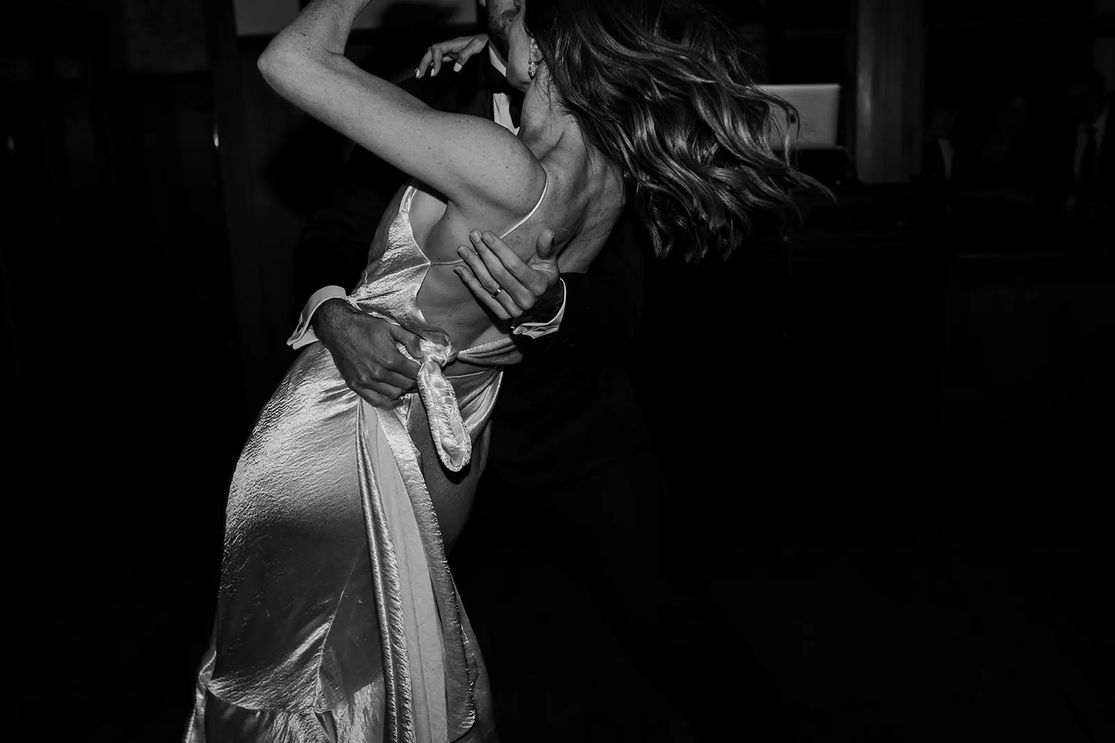 Black and white photo of a bride dancing, her long waves flying