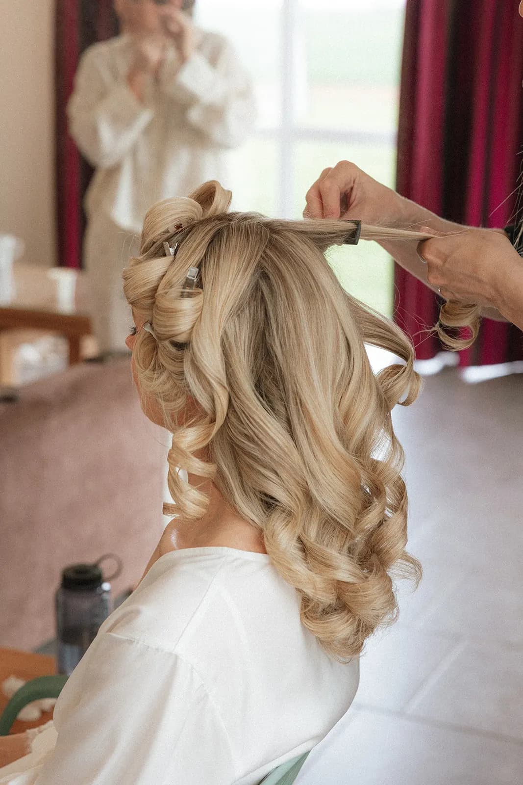 Stacey pinning big barrel curls into a client's blonde hair